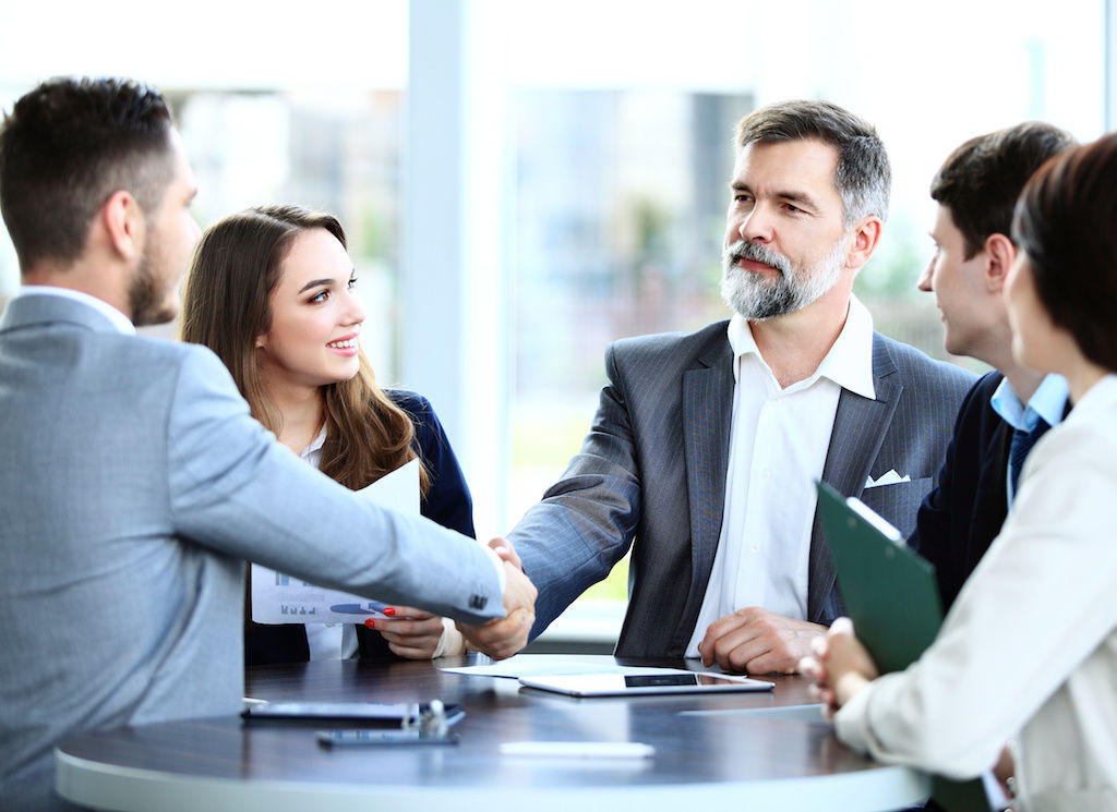 Five business professionals gathered around table at industry event